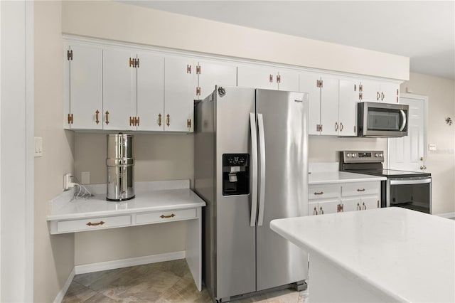kitchen featuring light countertops, white cabinets, appliances with stainless steel finishes, and baseboards