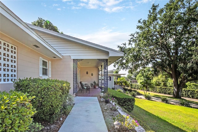 view of exterior entry featuring covered porch and a lawn