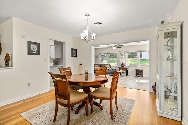 dining area featuring ceiling fan with notable chandelier, light wood-type flooring, visible vents, and baseboards