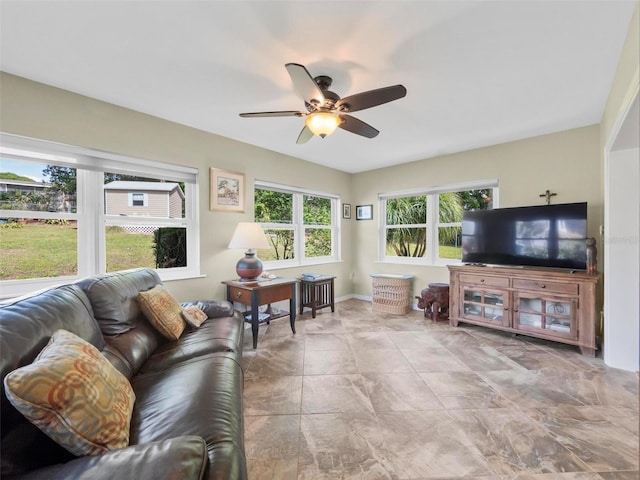 living area with baseboards and ceiling fan