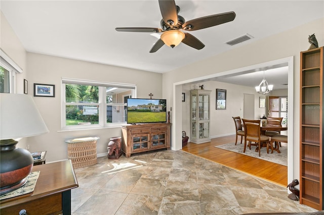living room featuring wood finished floors, ceiling fan with notable chandelier, a healthy amount of sunlight, and visible vents