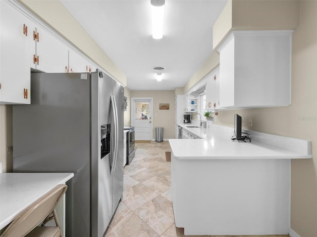 kitchen featuring light countertops, a peninsula, stainless steel appliances, white cabinetry, and a sink