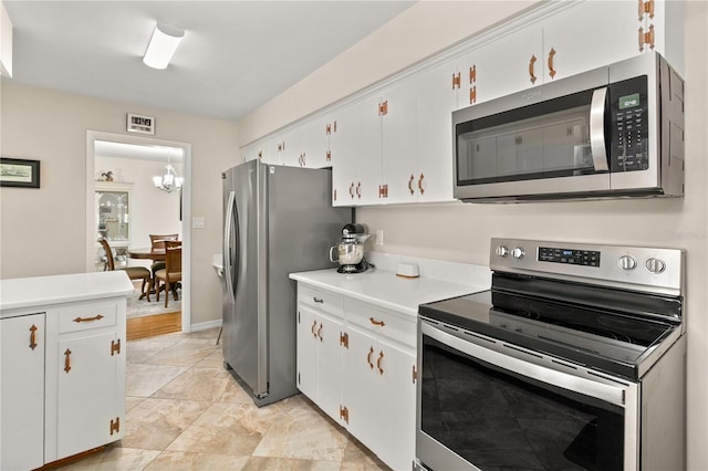 kitchen with white cabinets, an inviting chandelier, light countertops, and stainless steel appliances