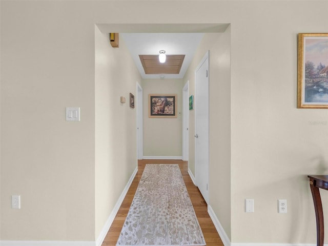 hallway featuring baseboards and wood finished floors