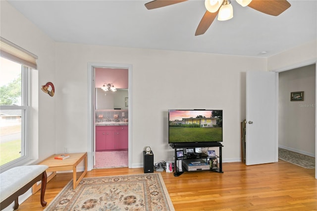 living room with light wood finished floors, baseboards, and ceiling fan