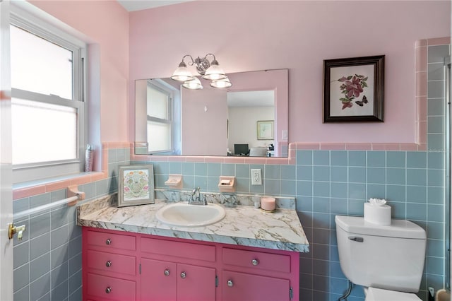 bathroom featuring a wainscoted wall, a notable chandelier, toilet, vanity, and tile walls