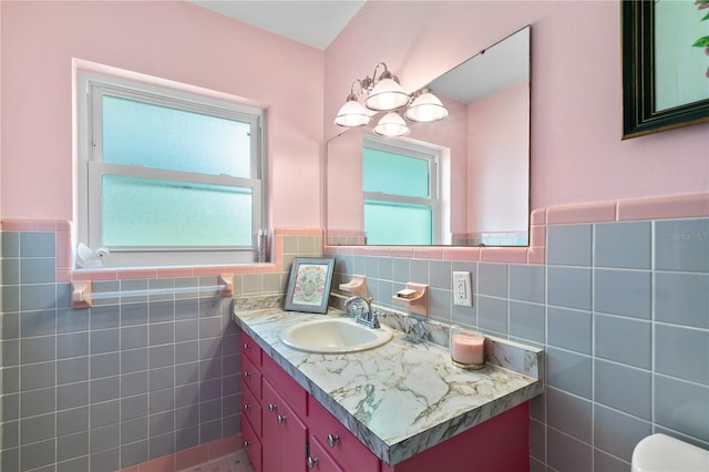 bathroom with tile walls, toilet, vanity, and wainscoting