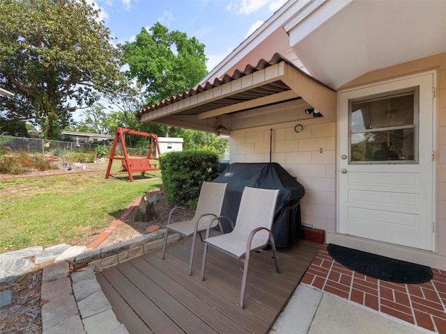 wooden terrace with fence, area for grilling, and a yard