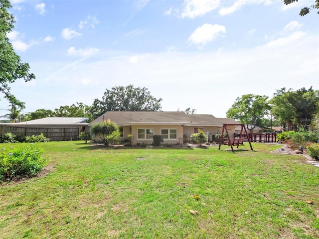 back of property with fence and a lawn
