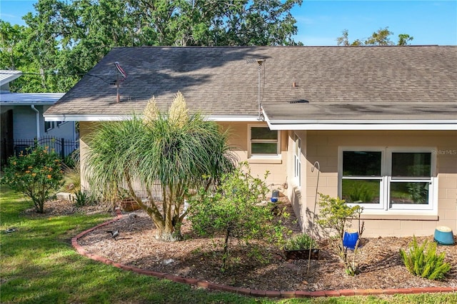 view of side of property featuring concrete block siding and roof with shingles