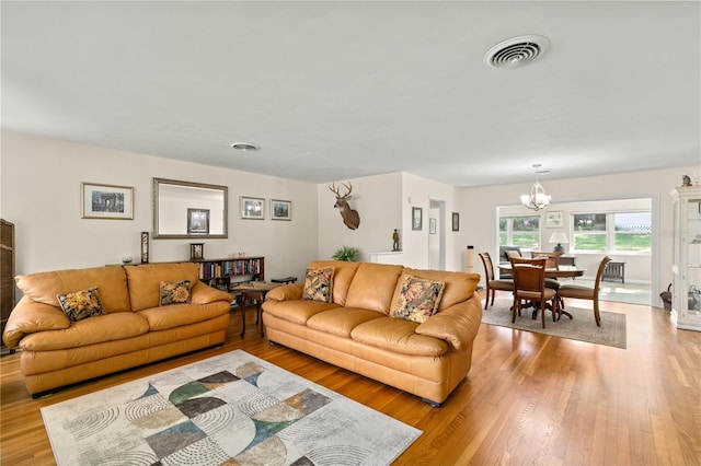 living area with light wood-style floors, a chandelier, and visible vents