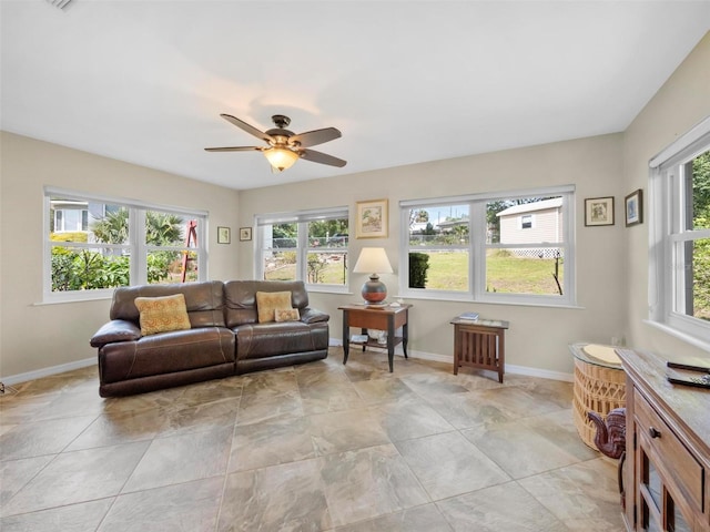living area featuring baseboards and a ceiling fan