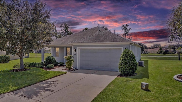 single story home with a garage, concrete driveway, stucco siding, roof with shingles, and a lawn