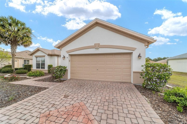 view of front of house featuring decorative driveway, stucco siding, and an attached garage