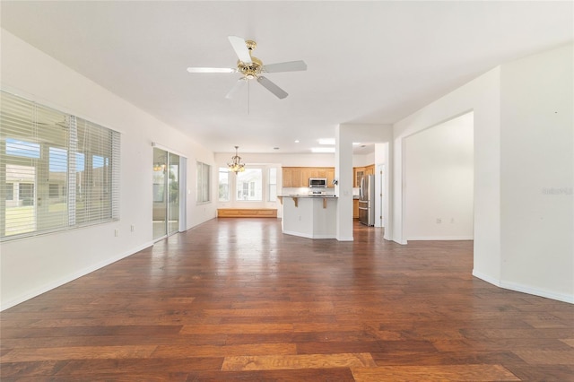 unfurnished living room with dark wood-style floors, baseboards, and ceiling fan with notable chandelier