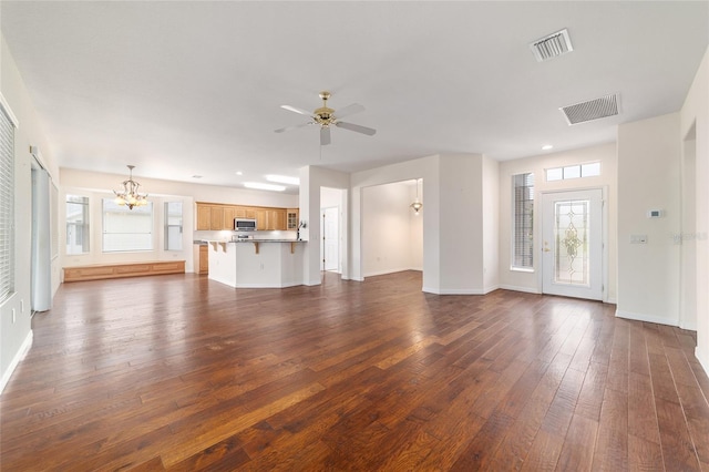 unfurnished living room featuring ceiling fan with notable chandelier, dark wood-style floors, baseboards, and visible vents