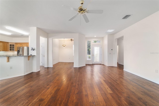 unfurnished living room featuring visible vents, baseboards, ceiling fan, and dark wood finished floors