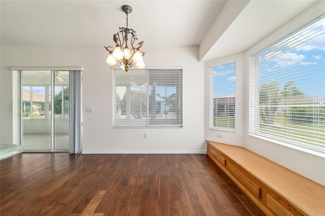 unfurnished dining area featuring dark wood-type flooring, baseboards, and a notable chandelier