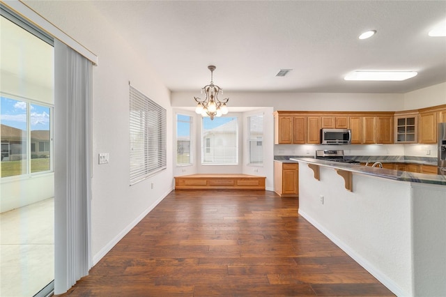 kitchen with an inviting chandelier, stainless steel appliances, a breakfast bar, visible vents, and glass insert cabinets