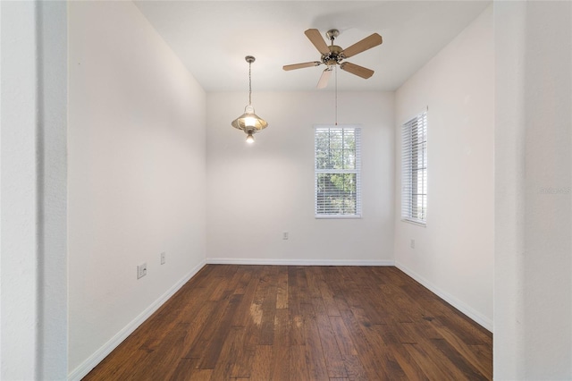 empty room featuring baseboards, a ceiling fan, and dark wood-style flooring
