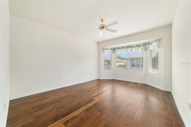 empty room with dark wood-style floors, baseboards, and ceiling fan