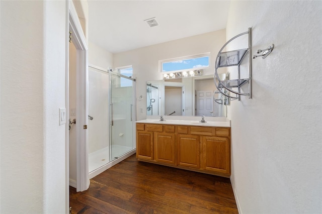 bathroom with double vanity, a sink, hardwood / wood-style flooring, and a shower stall