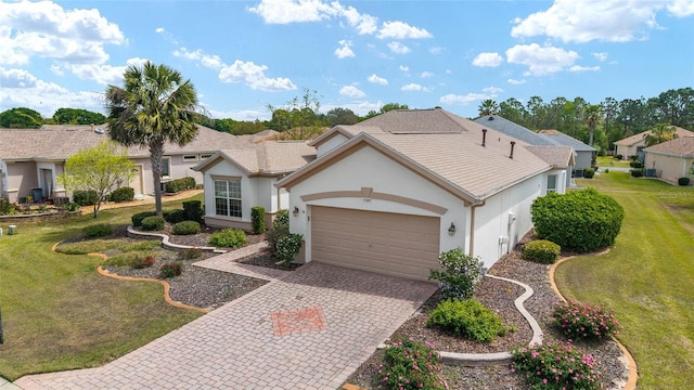 view of front of property with stucco siding, an attached garage, a front yard, and decorative driveway