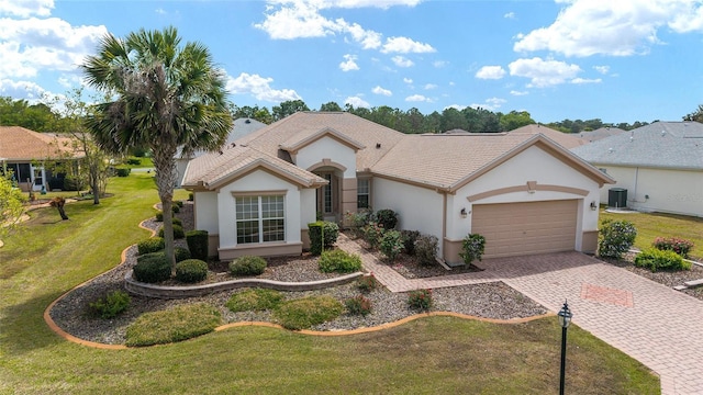 view of front of home with stucco siding, central air condition unit, decorative driveway, a front lawn, and a garage