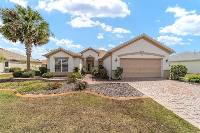 mediterranean / spanish-style house with a garage, decorative driveway, stucco siding, and a front lawn