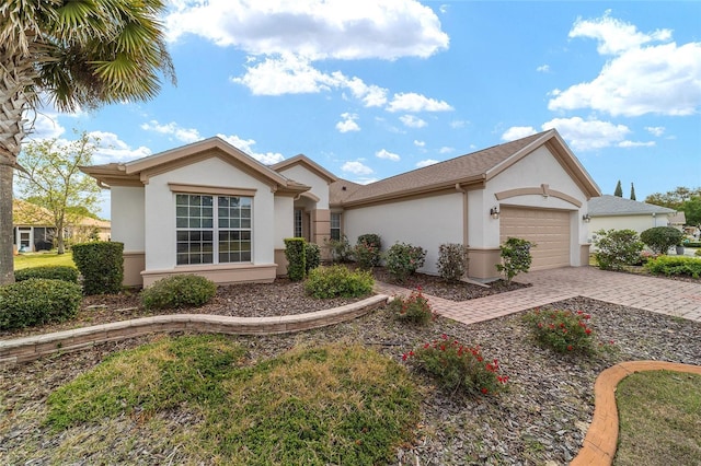 ranch-style house featuring stucco siding, a garage, and decorative driveway