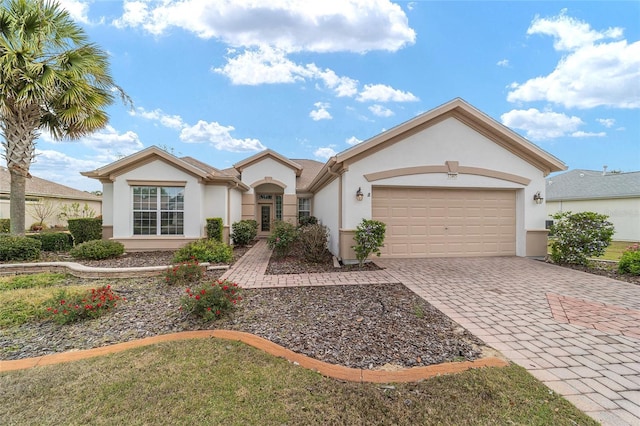 view of front of house with decorative driveway, an attached garage, and stucco siding