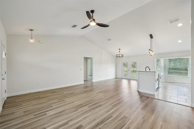 2575 SE 75th Blvd, Bushnell, FL 33513 - unfurnished living room featuring vaulted ceiling, ceiling fan with notable chandelier, light wood finished floors, and visible vents