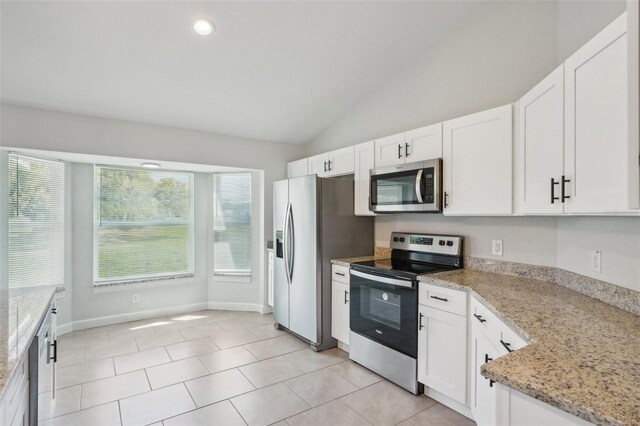 2575 SE 75th Blvd, Bushnell, FL 33513 - kitchen with white cabinetry, light stone countertops, lofted ceiling, light tile patterned floors, and stainless steel appliances
