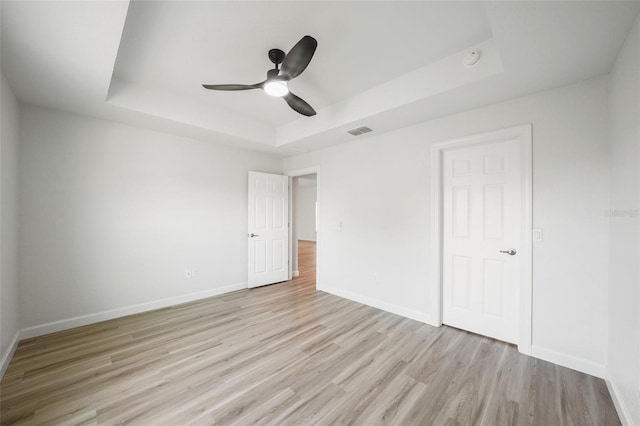 2575 SE 75th Blvd, Bushnell, FL 33513 - unfurnished bedroom with light wood-type flooring, a raised ceiling, baseboards, and visible vents