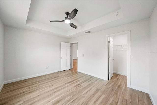 2575 SE 75th Blvd, Bushnell, FL 33513 - unfurnished bedroom featuring baseboards, a tray ceiling, visible vents, and light wood finished floors