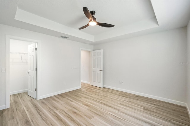 2575 SE 75th Blvd, Bushnell, FL 33513 - unfurnished bedroom with a ceiling fan, a raised ceiling, light wood-style flooring, baseboards, and visible vents