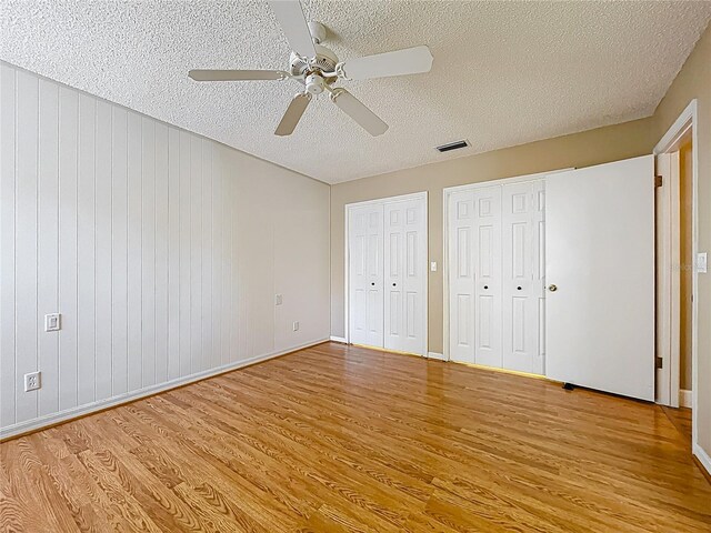 26823 Forest Hills St, Leesburg, FL 34788 - unfurnished bedroom featuring a textured ceiling, a ceiling fan, light wood-style floors, visible vents, and multiple closets