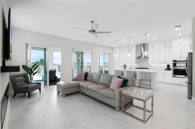 living room with light tile patterned flooring, a wealth of natural light, visible vents, and a ceiling fan