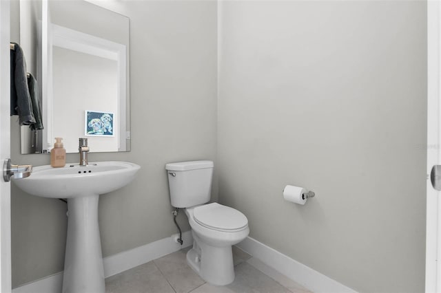 half bathroom with tile patterned floors, toilet, and baseboards