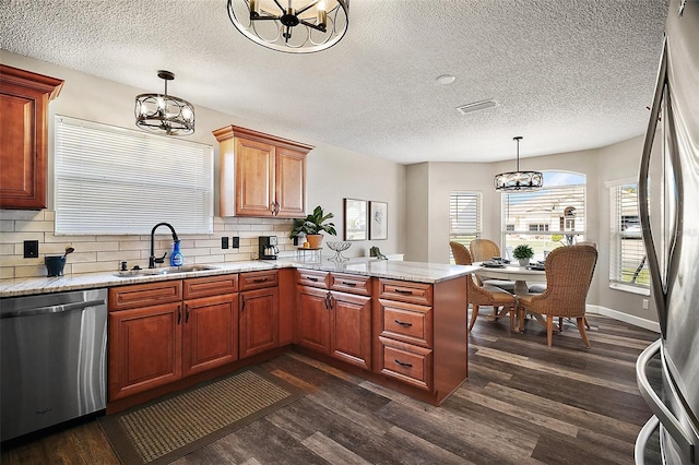 2142 Margarita Dr, The Villages, FL 32159 - kitchen with dark wood-style flooring, a chandelier, a sink, a peninsula, and appliances with stainless steel finishes