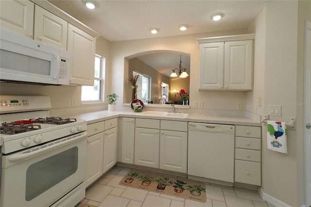 kitchen featuring white appliances, light countertops, a sink, and white cabinetry