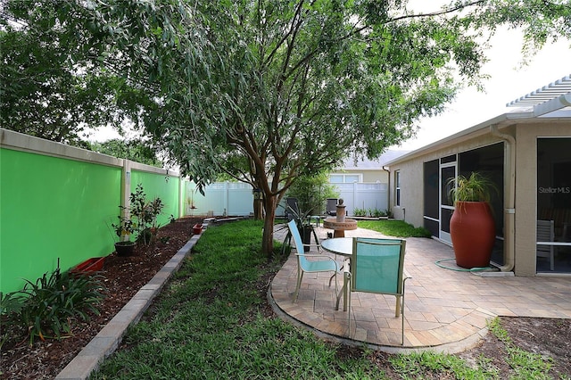 view of yard featuring a sunroom, a patio, and a fenced backyard