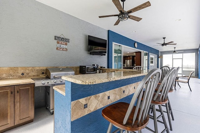 11619 Lane Park Rd, Tavares, FL 32778 - kitchen featuring a breakfast bar area, ceiling fan, and a textured wall