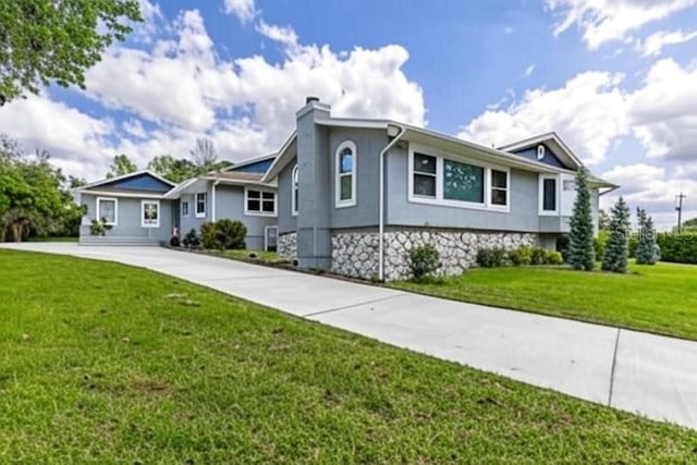 11619 Lane Park Rd, Tavares, FL 32778 - view of front of home with concrete driveway, a chimney, a front yard, and stucco siding