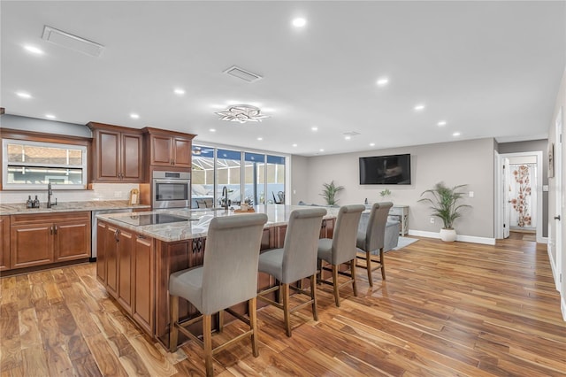 11619 Lane Park Rd, Tavares, FL 32778 - kitchen with light stone countertops, a breakfast bar area, an island with sink, appliances with stainless steel finishes, and light wood-style floors