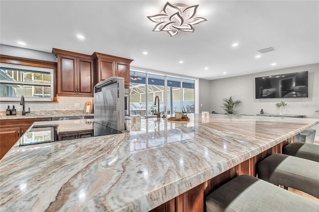 11619 Lane Park Rd, Tavares, FL 32778 - kitchen featuring a breakfast bar area, light stone counters, healthy amount of natural light, and recessed lighting