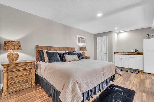 11619 Lane Park Rd, Tavares, FL 32778 - bedroom with freestanding refrigerator, light wood-style floors, a textured ceiling, a wall unit AC, and recessed lighting