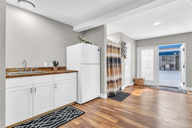 11619 Lane Park Rd, Tavares, FL 32778 - kitchen with freestanding refrigerator, light wood-style floors, a textured wall, butcher block counters, and white cabinets