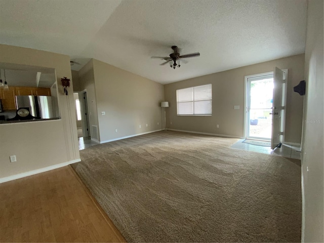 664 San Pedro Dr, The Villages, FL 32159 - unfurnished living room featuring vaulted ceiling, light colored carpet, baseboards, a textured ceiling, and a ceiling fan