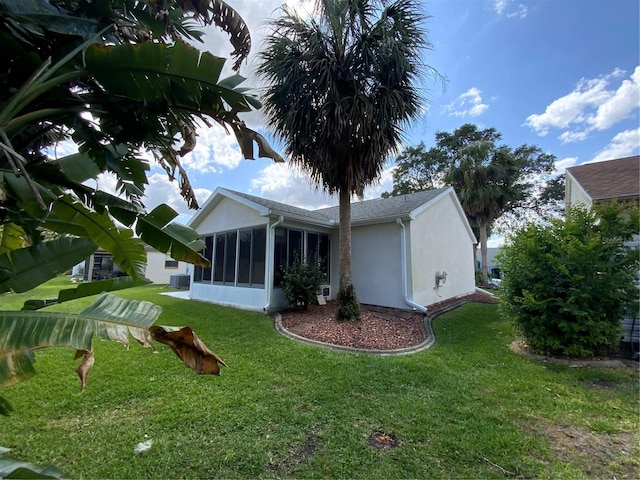 664 San Pedro Dr, The Villages, FL 32159 - back of property featuring stucco siding, a sunroom, central air condition unit, and a lawn
